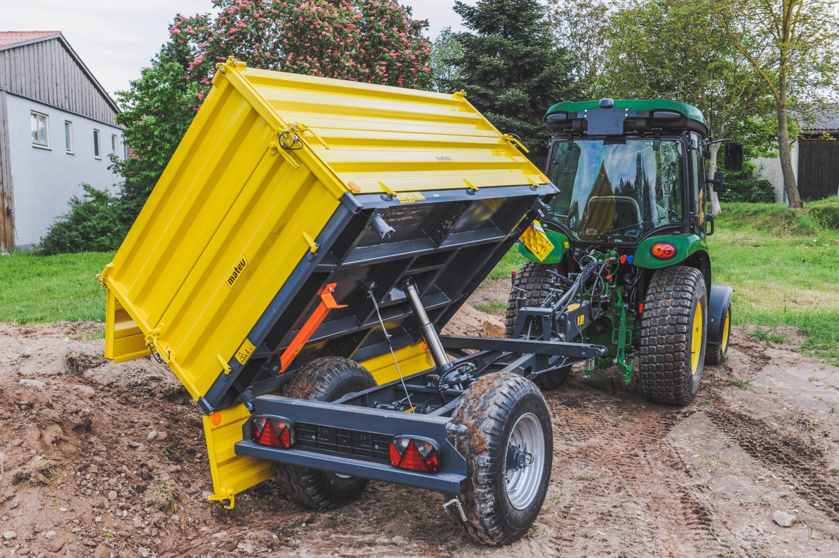 Anhänger in der Farbe Gelb für Traktoren in der Kommunaltechnik. Der gerade Schuttgut abliefert.