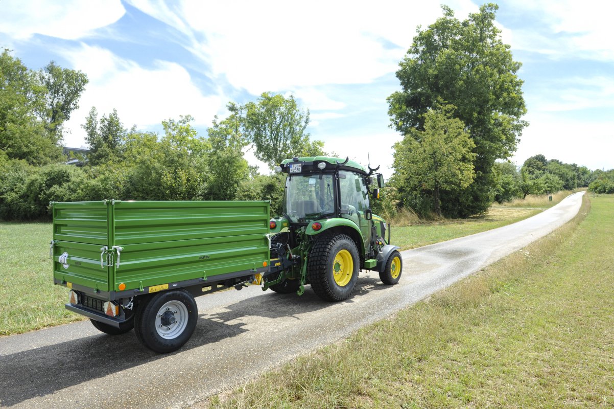 Anhänger in der Farbe grün für Traktoren in der Kommunaltechnik. An einem John Deere montiert.