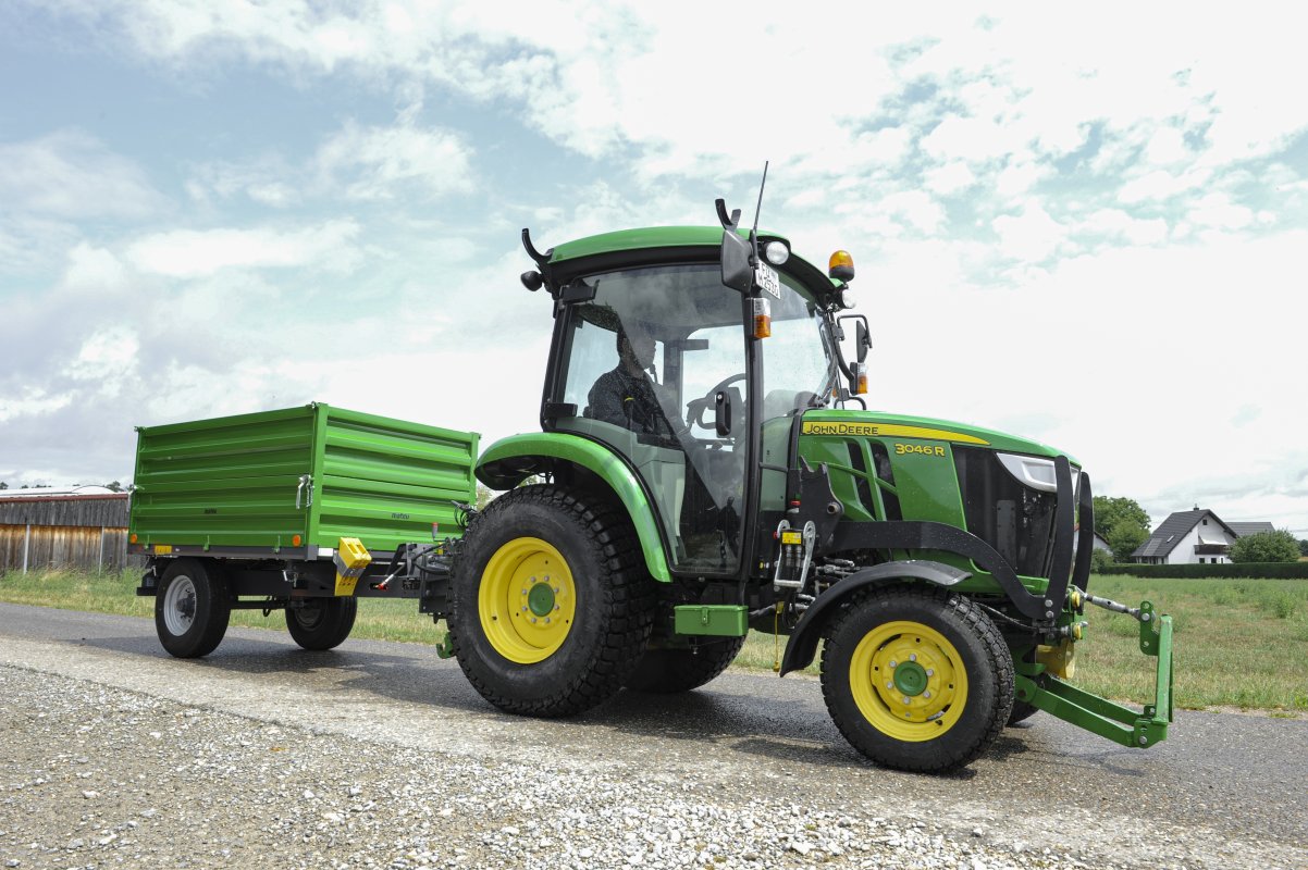 Anhänger in der Farbe grün für Traktoren in der Kommunaltechnik. An einem John Deere montiert.