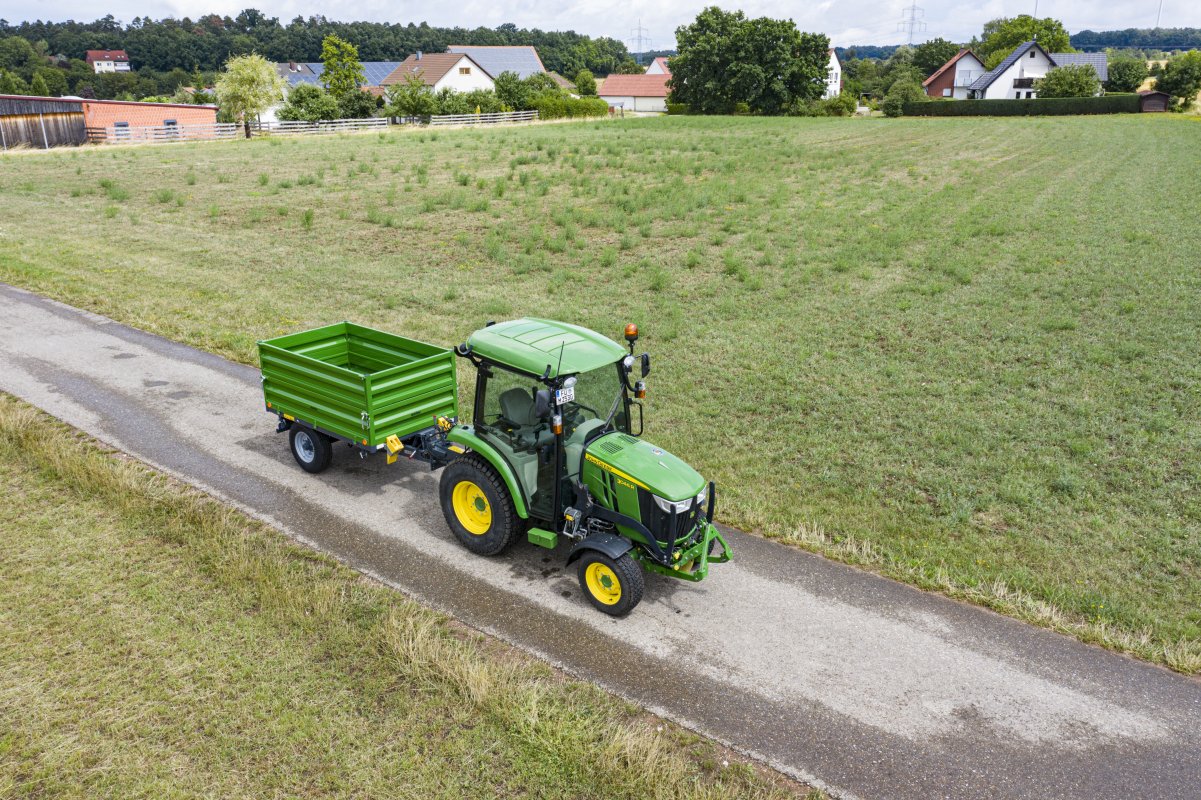 Anhänger in der Farbe grün für Traktoren in der Kommunaltechnik. An einem John Deere montiert.